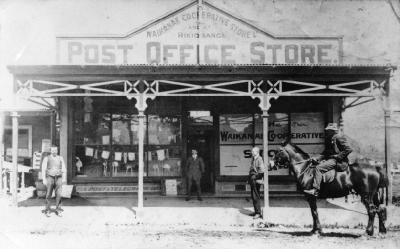 Historical photo of the old Waikanae Cooperative Store - Post Office Store, with three men standing outside, and one man on horseback