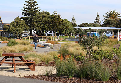 Image showing a person walking on a path through the Maclean Park plantings, with structures and trees in the background