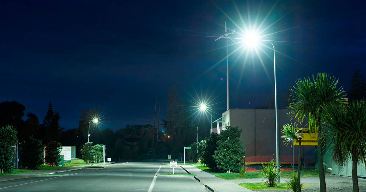 Photo of a quiet street at night, lit by streetlights.