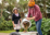 Photo of a community member from Paekākāriki wearing a cycle helmet, picking up compost and putting it into a bike trailer, while a woman watches on.