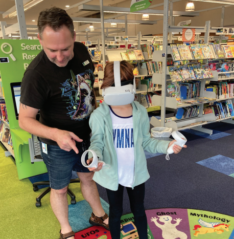 Photo of one of our librarians helping a young user with a Virtual Reality headset.