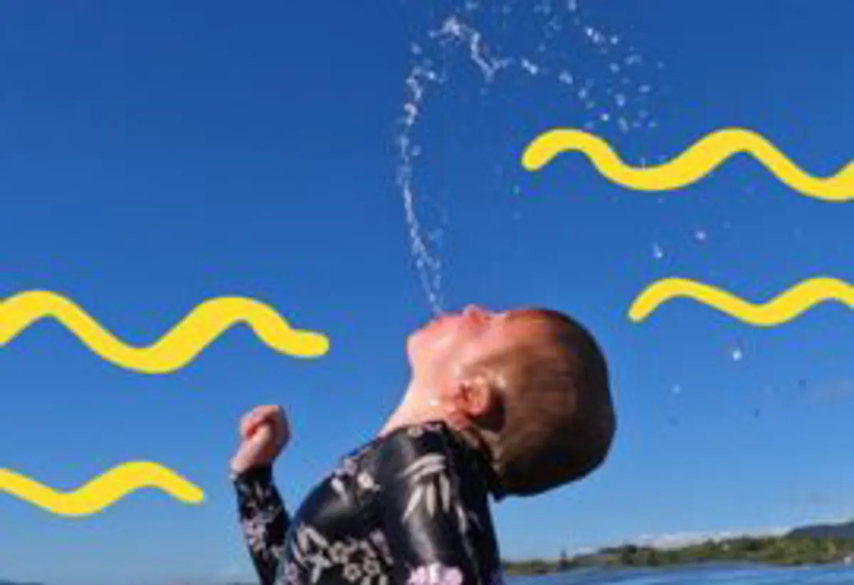 Boy flicking hair and spitting out water at the beach 