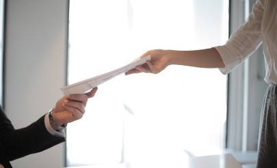 Person handing documents to another person