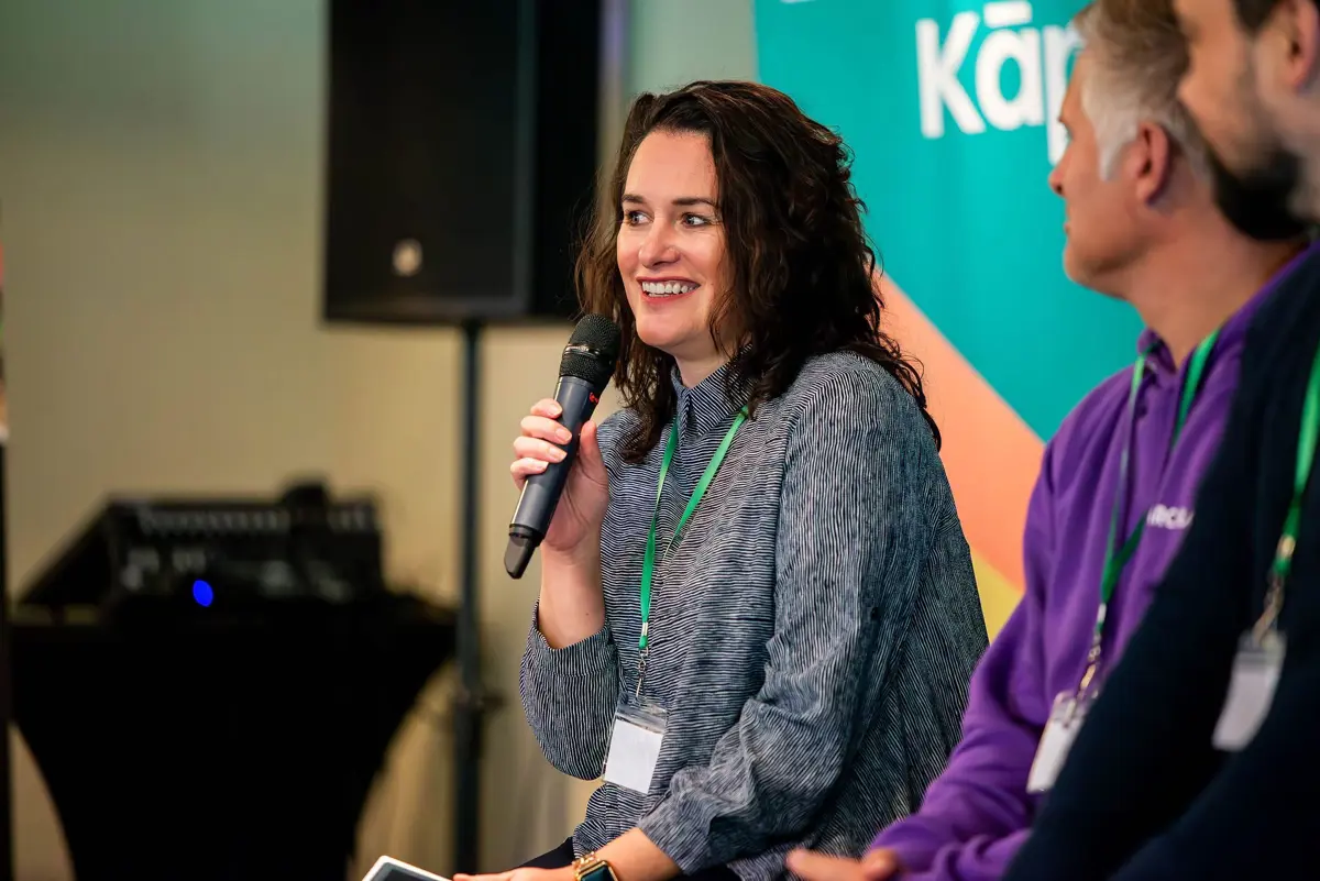 techweek presenter 2025 sitting on a panel holding a microphone