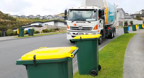 Waste Management truck approaching recycling bins on the kerbside.