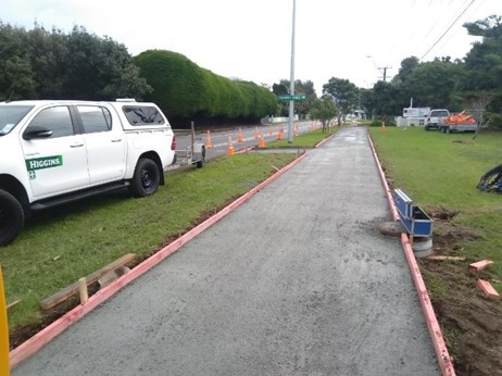 Photo showing construction of the shared path, looking from the golf club entrance towards the beach, with a contractor vehicle parked beside the newly laid cement path.