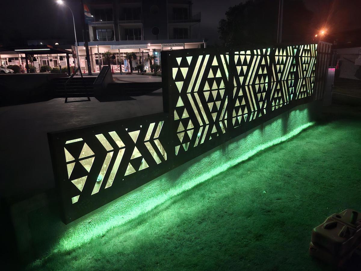 Waharua by artist Kereama Taepa lit green at night. 