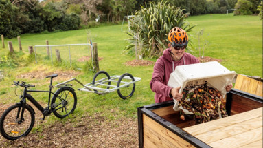 Paekākāriki Community Orchard and Gardens (POG) member Spencer Crocker empties locally collected compost into the community bin.