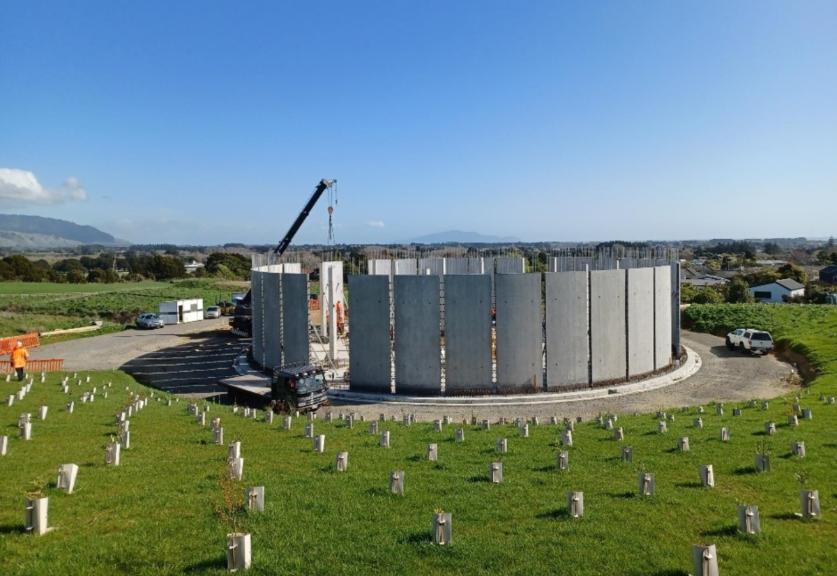 A crane puts the last wall panel in place on the Ōtaki Reservoir and the bund around the reservoir has been planted with native plants.