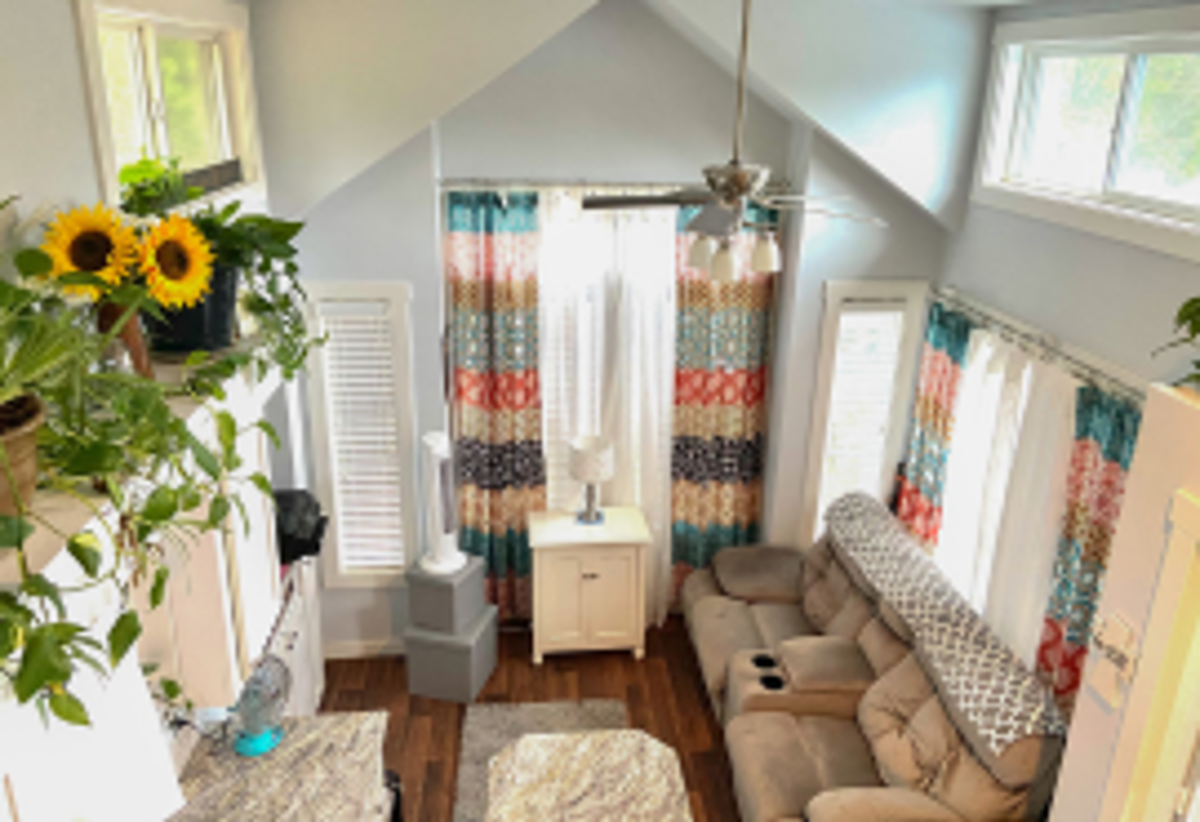 Photo of the interior of a tiny home living room, looing down on the seating area from near the roof.