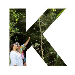 Photo in the shape of the letter "K", with two women looking at native bush.