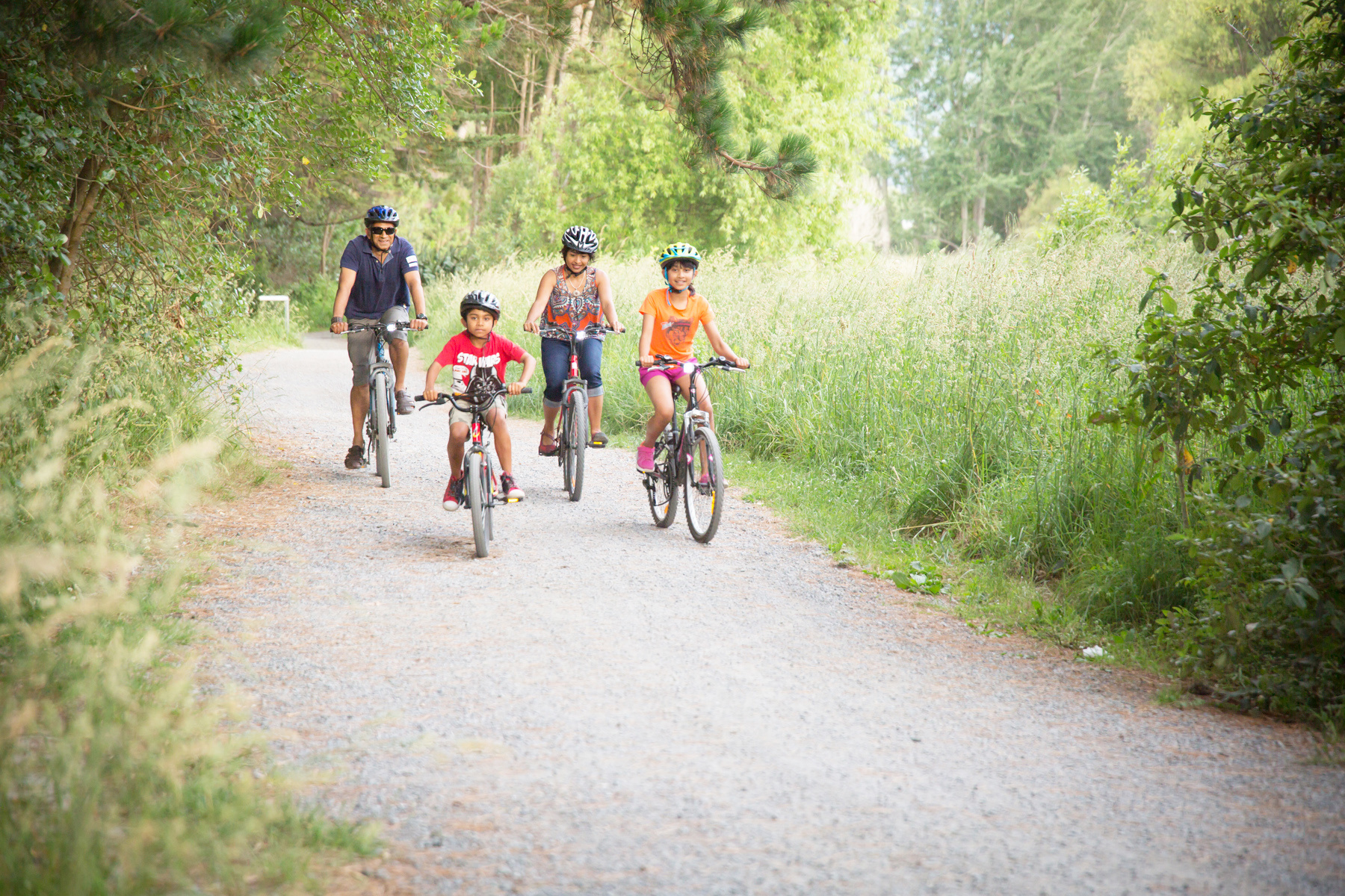 Photo of a family biking under willow trees on the Waikanae River track