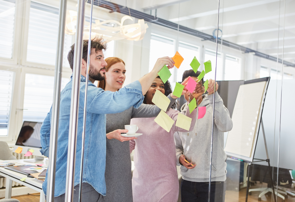 Participants working together in a bid readiness workshop, adding notes to a glass board