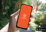 Photo of a hand holding a smartphone with the Antenno opening screen displayed. The bottom right corner of the photo has the "Download on the App Store" and "Get it on Google Play" logos.