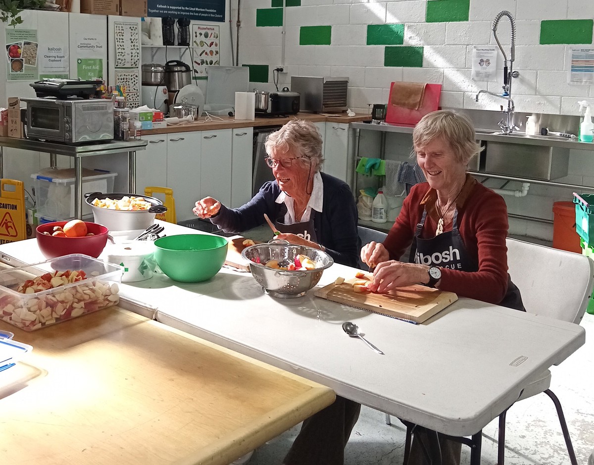 Kaibosh volunteers Penny and Jill cutting apples at a kitchen table.