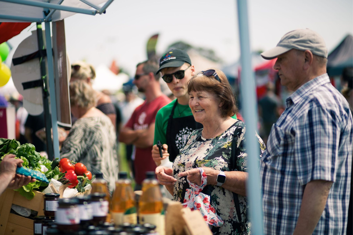 A couple purchasing items from a stall holder at the Kāpiti Food Fair