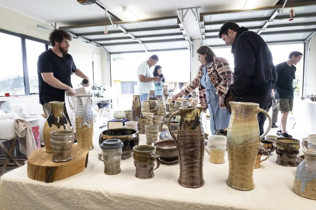 Visitors viewing handmade pottery and ceramics at an Art Trail studio exhibition.