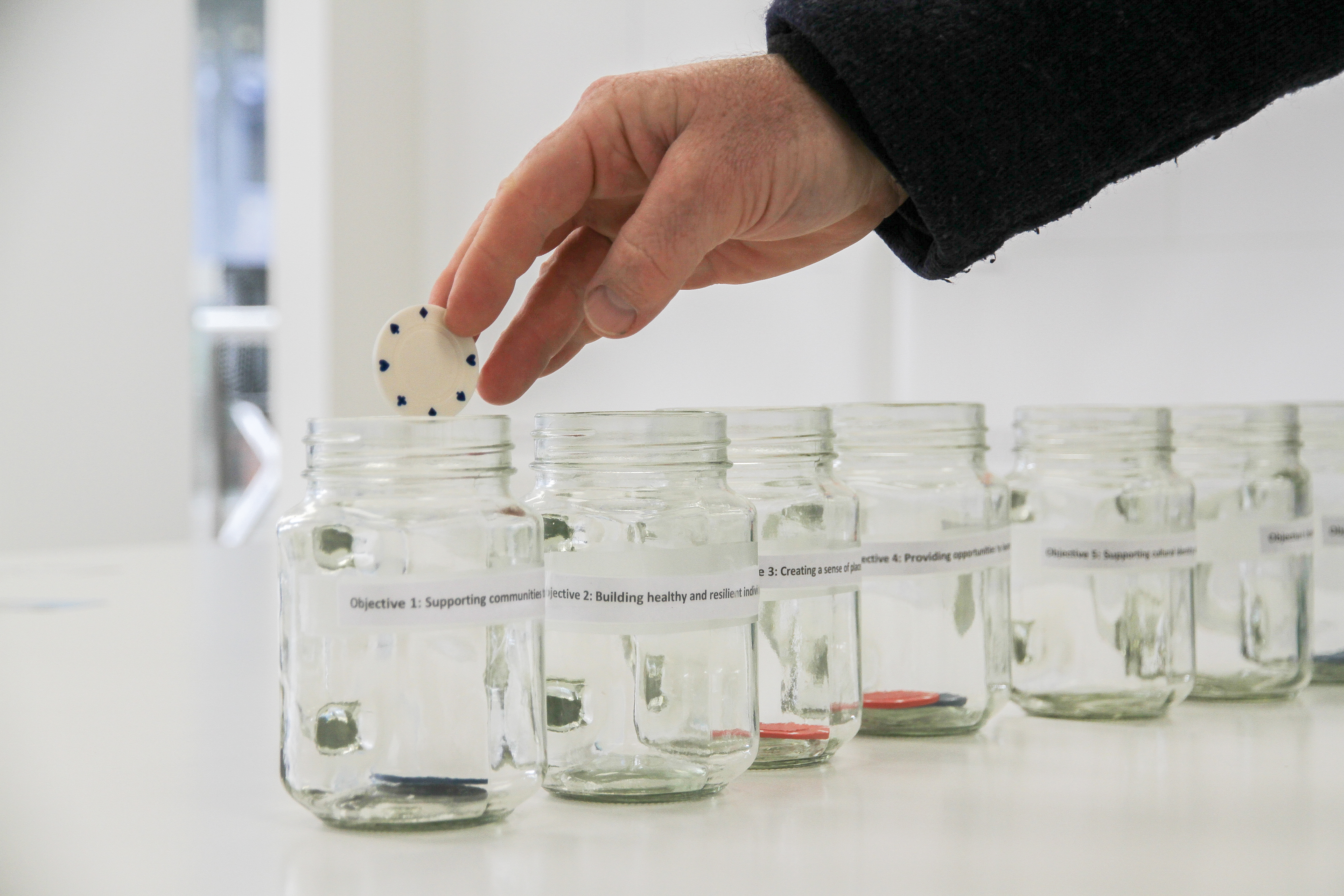 Hand putting a token in a jar for specific options.